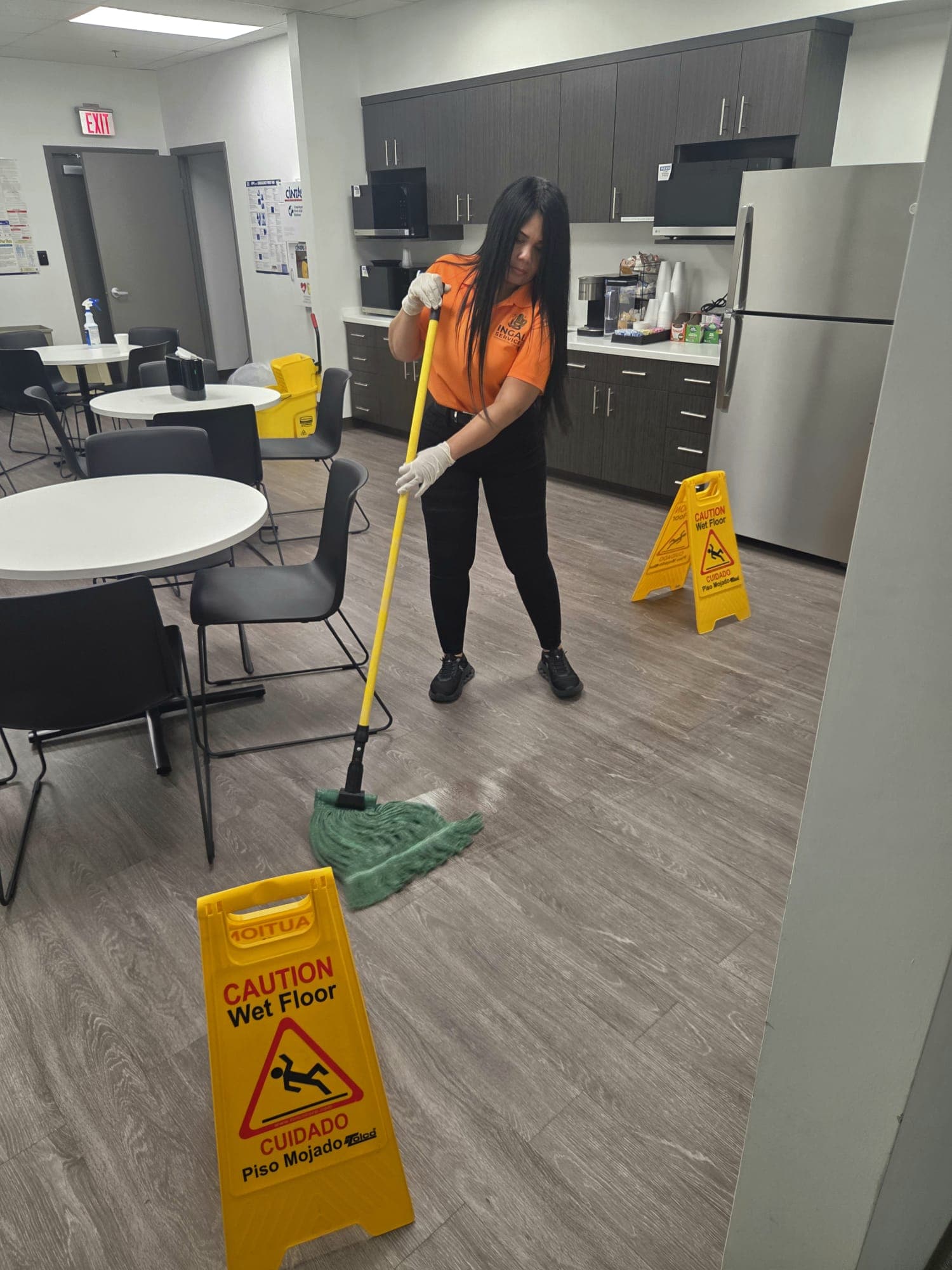 INGAL SERVICES INC employee damp mopping a client breakroom with wet floor signage in place